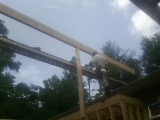 Carpenter setting a ridge beam over a new addition frame — Ice Dam Removal by Roofing Brothers in Payne
