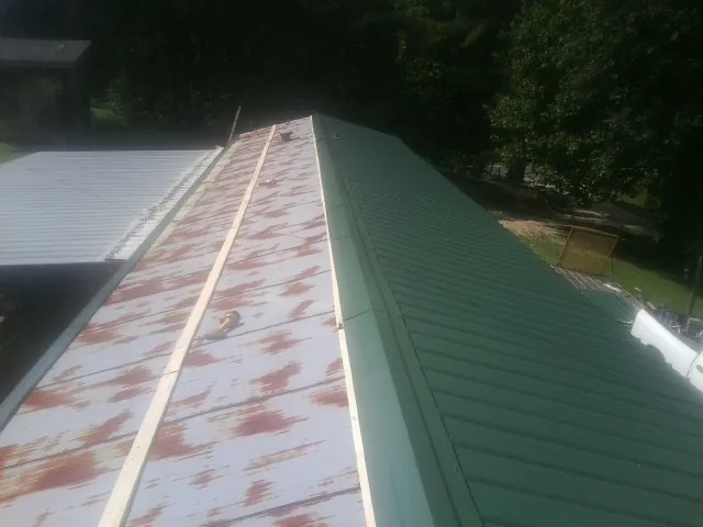 Old rusted panels beside newly installed green metal roofing — Wind Damage Roof Repair by Roofing Brothers in Payne