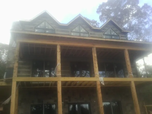 Dormers and porch framing on a large log home under construction — Roof Coating work by our crew in Payne