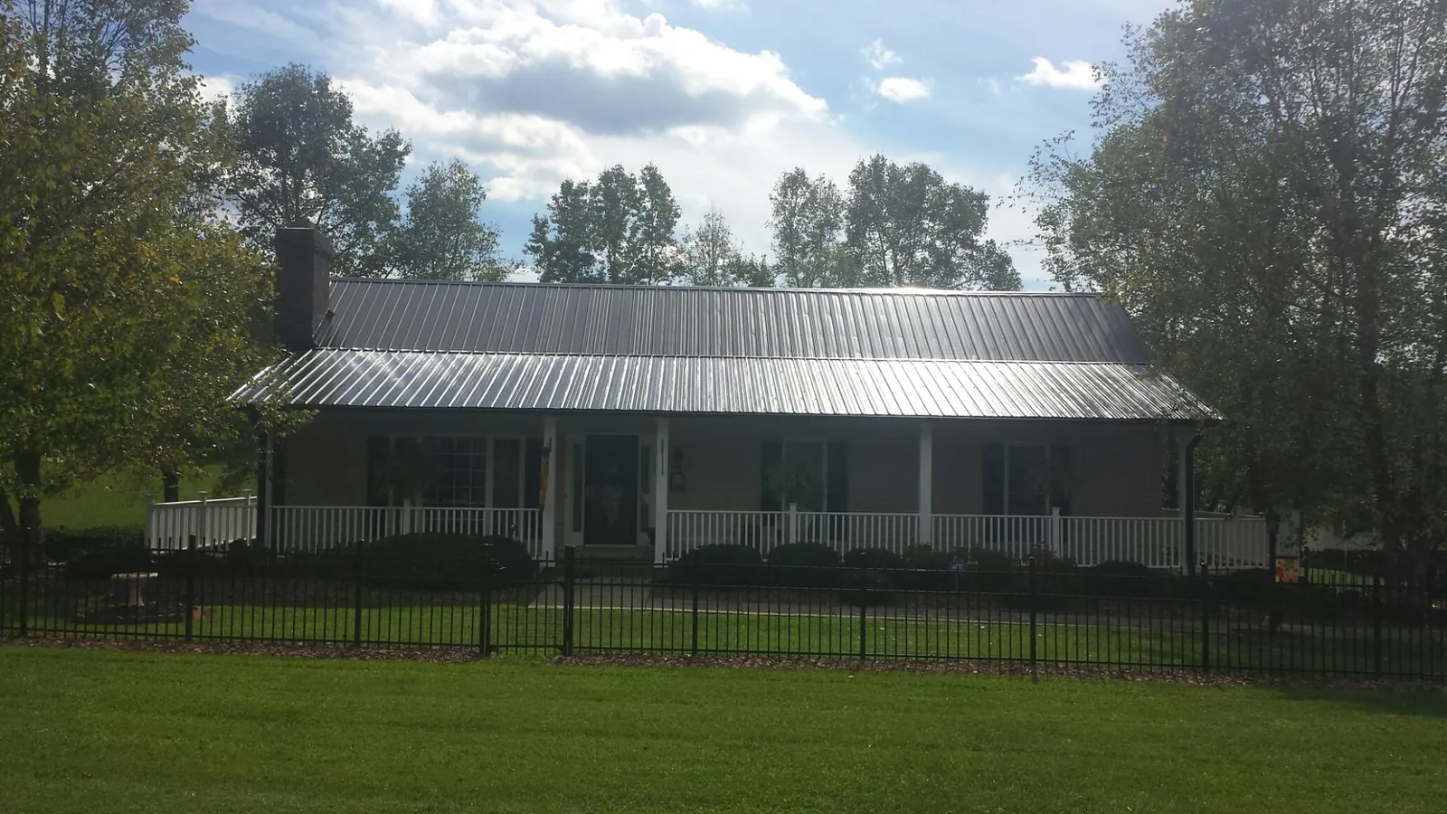 Gray metal roof on a brick ranch with a full width front porch — Gutter Guard Installation work by our crew in Payne